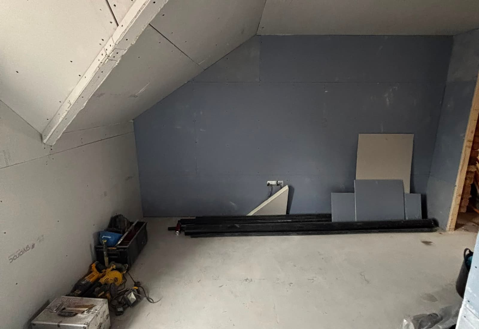 Loft conversion in progress on an SMM job — sloped ceilings freshly plasterboarded with the stub wall framed out